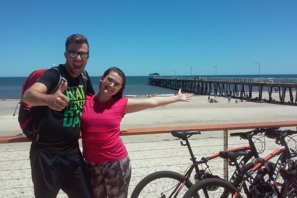 cyclist taking a break at henley beach with two mountain bikes against balustrade 